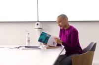 Collaboratrice seule dans une salle de réunion devant son laptop avec feuilles de notes et gourde