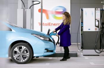 Woman charging her vehicle at electric station