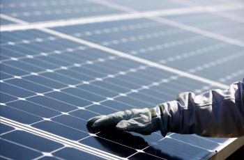 Gloved hand on a solar panel of the photovoltaic plant commissioned by ISE, Total and SunPower. Nanao, Japan.